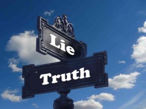 A street sign with 'lie' written on it, and another with the word 'truth'.