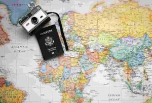 A passport and camera atop of a world map